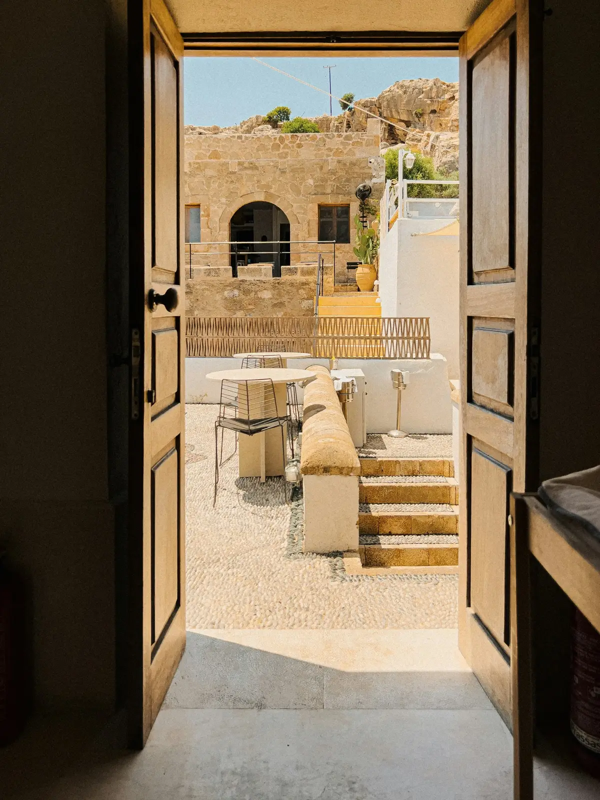 Puerta abierta a un patio de piedra soleado, una vivienda ya transformada
