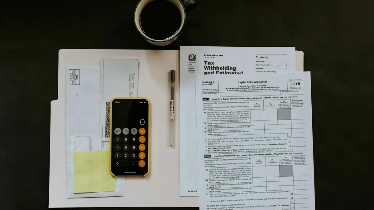 Documentación fiscal, bolígrafo y móvil sobre una carpeta blanca en un escritorio