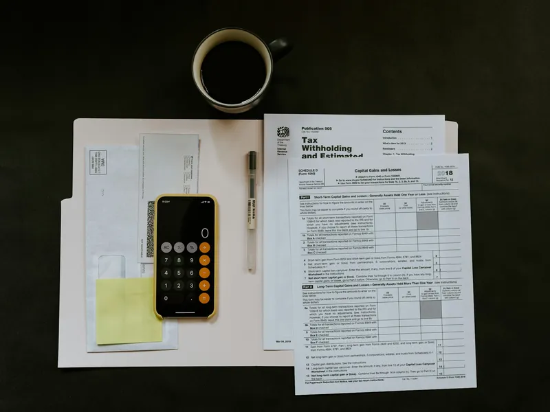 Documentación fiscal, bolígrafo y móvil sobre una carpeta blanca en un escritorio