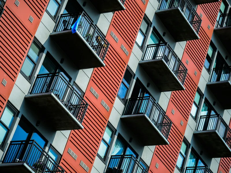 Edificio de viviendas alto en tonos rojos con balcones