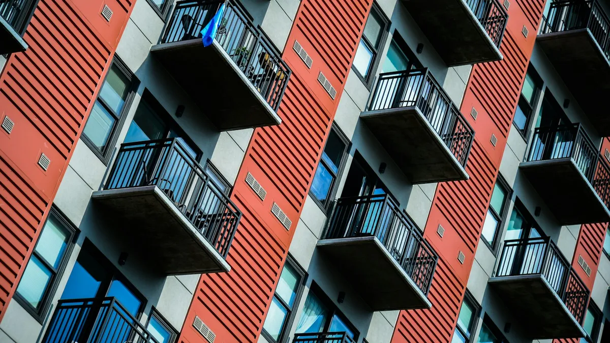 Edificio de viviendas alto en tonos rojos con balcones